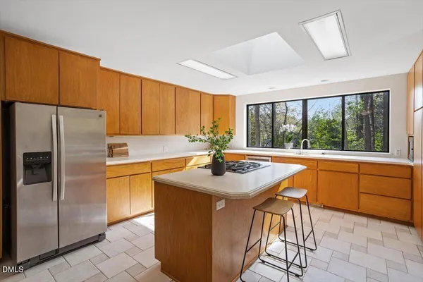 a kitchen with stainless steel appliances granite countertop a sink a stove a refrigerator a washer dryer and a dining table with wooden cabinet