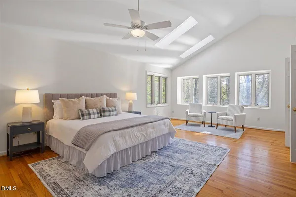 a spacious bedroom with a large bed a chandelier and windows