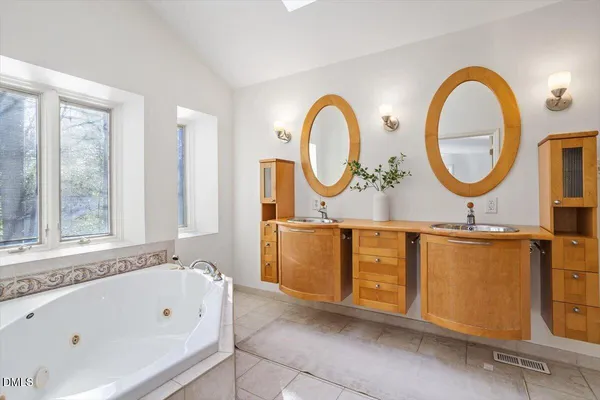 a bathroom with a tub a double vanity sink a mirror and a window