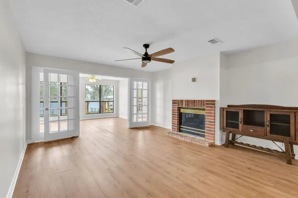 a view of a livingroom with a fireplace a ceiling fan and wooden floor