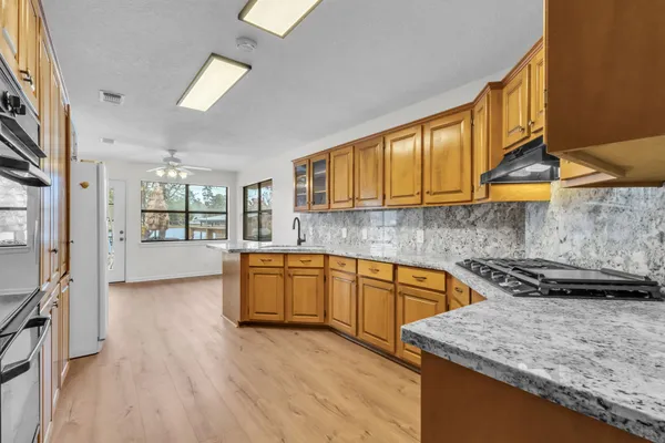 a kitchen with stainless steel appliances granite countertop wooden cabinets a stove top oven a sink and dishwasher