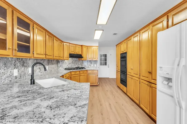 a view of a kitchen with stainless steel appliances granite countertop a sink and a refrigerator
