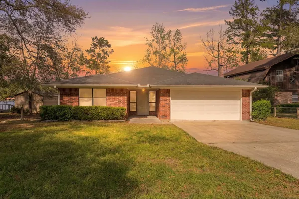 a view of yellow house with a big yard and large trees
