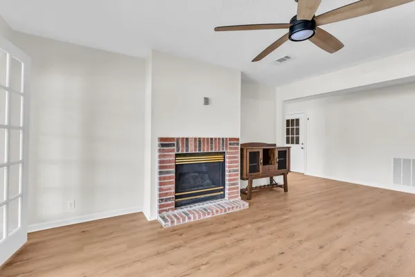a view of an empty room with fire place and a window