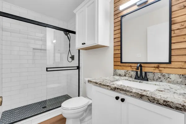 a bathroom with a granite countertop sink toilet and shower