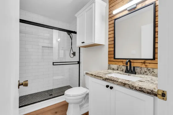a bathroom with a granite countertop sink toilet and mirror