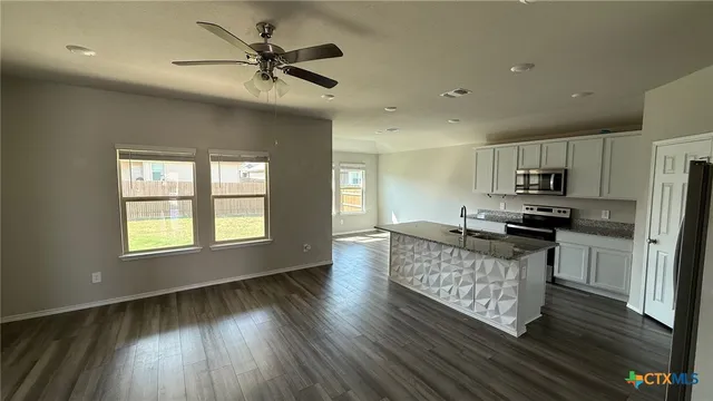 a kitchen with kitchen island granite countertop a stove a refrigerator and a sink