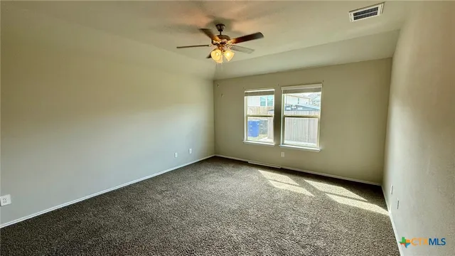 en empty room with windows and fan