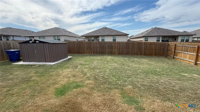 a view of a house with a yard and wooden fence