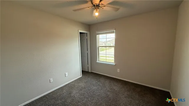 an empty room with a ceiling fan and window