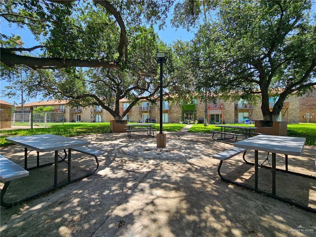 2201 South Jackson Road, Unit 2I Pharr, TX 78577 - Photo 19 of 23 Outdoor common area featuring multiple picnic tables with benches, mature shade trees, and paved ground