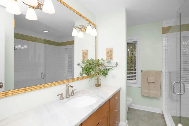 a bathroom with a granite countertop sink a mirror and a shower