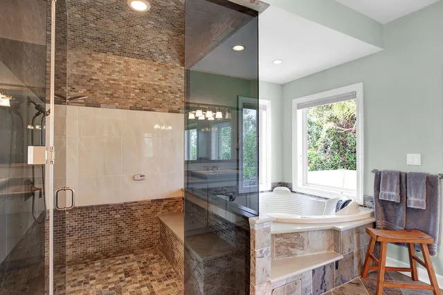 a bathroom with a sink vanity granite tub shower and a mirror