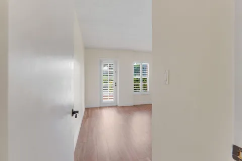 a view of an empty room with a window and wooden floor