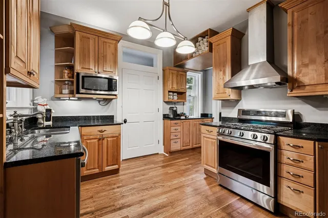 a kitchen with stainless steel appliances granite countertop a stove top oven a sink dishwasher and white cabinets with wooden floor