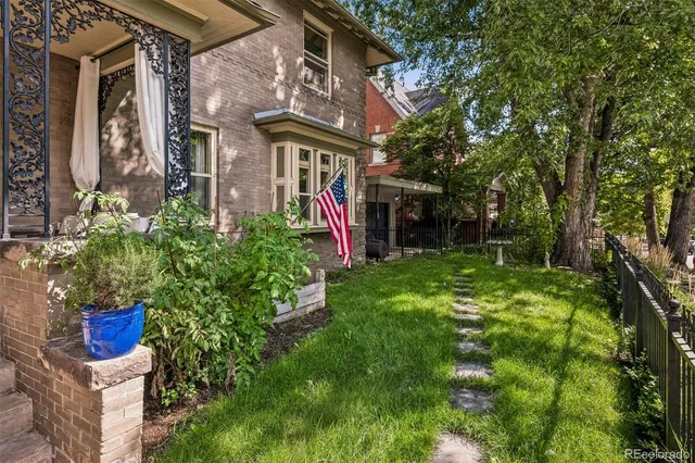 a view of brick house with a yard and plants