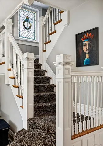a view of staircase with lots of frames on wall and a rug