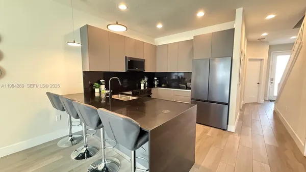 a kitchen with stainless steel appliances granite countertop a sink a refrigerator and a stove top oven with wooden floor