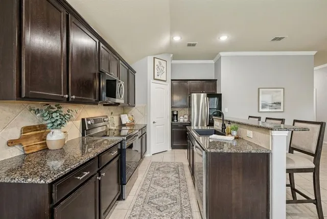 a large kitchen with granite countertop lots of counter space and stainless steel appliances