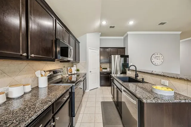 a kitchen with granite countertop stainless steel appliances a sink stove refrigerator and cabinets