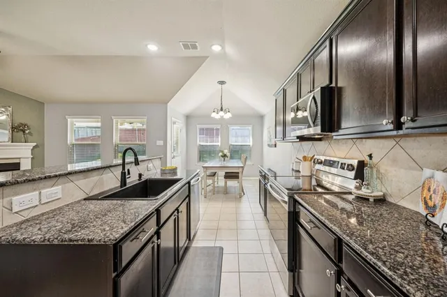 a kitchen with granite countertop stainless steel appliances a sink stove and cabinets