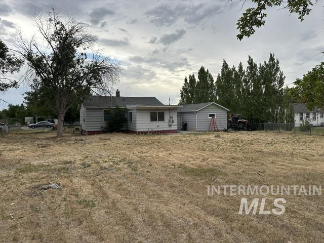 1301 Ridge Street Pocatello, ID 83201 - Photo 8 of 12 Spacious property featuring a single-story residence with light-colored siding, a detached utility building, a chain-link fence, and mature trees providing natural screening