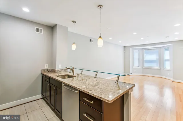 a kitchen with a sink a counter space and wooden floor