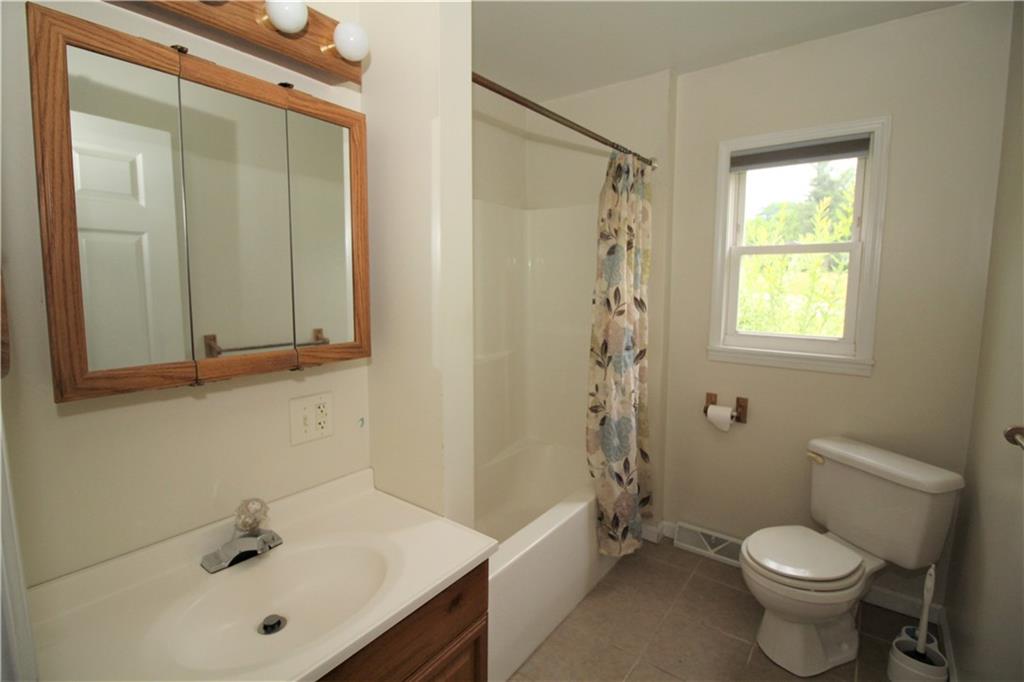 1456 Rte 481 Charleroi, PA 15022 - Photo 9 of 25 8x3 Full Bath next to Main Floor Bedrooms has a Space-Saving Corner Commode, Ceramic Tile Flooring, Tub/Shower Surround, and a Wooden Vanity & Medicine Cabinet & Light Bar.