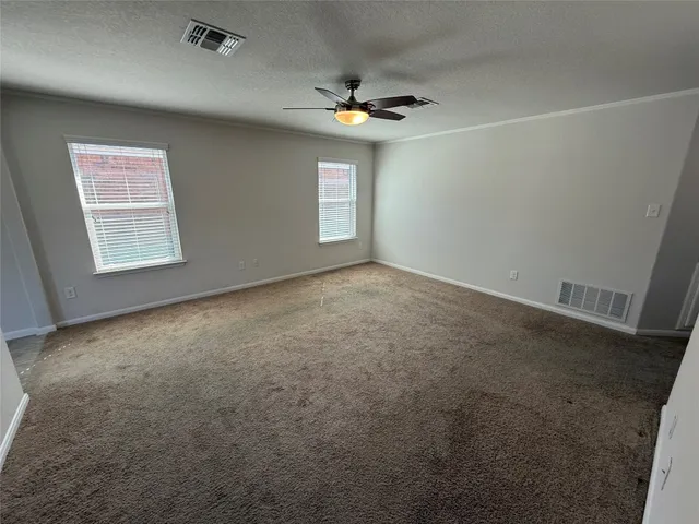 an empty room with a ceiling fan and windows