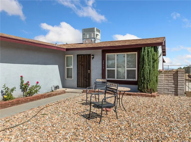 a patio with table and chairs and potted plants