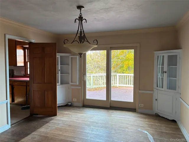 a view of an empty room with window and hardwood floor
