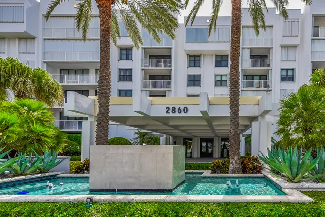 a front view of multi story residential apartment building with yard and green space
