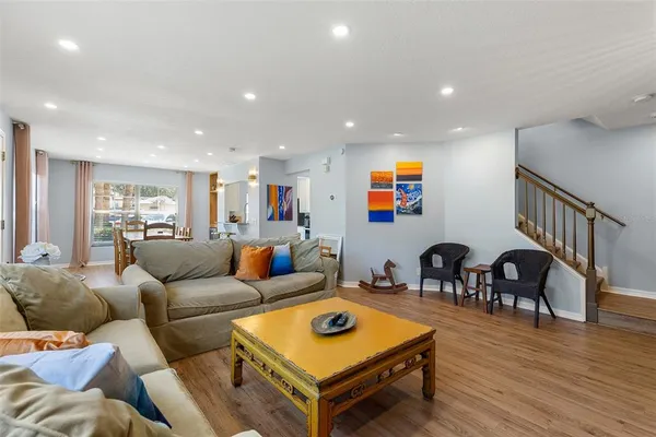 a living room with furniture kitchen view and a wooden floor