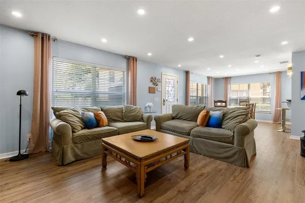 a living room with furniture a large window and wooden floor