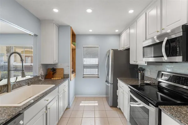 a kitchen with granite countertop a sink stainless steel appliances and cabinets