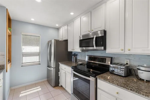 a kitchen with stainless steel appliances granite countertop a stove a sink and a microwave