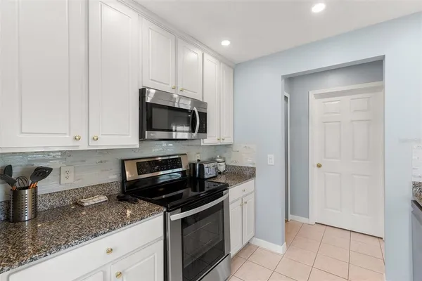 a kitchen with granite countertop white cabinets and stainless steel appliances