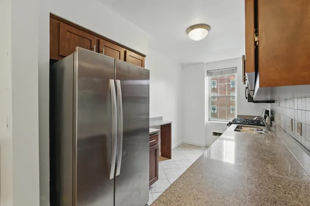 a kitchen with stainless steel appliances granite countertop a refrigerator a stove and a sink with wooden floor