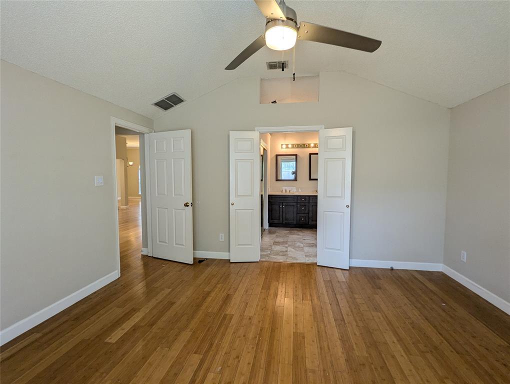 6019 Mapleshade Lane Dallas, TX 75252 - Photo 5 of 14 an empty room with wooden floor a ceiling fan and windows