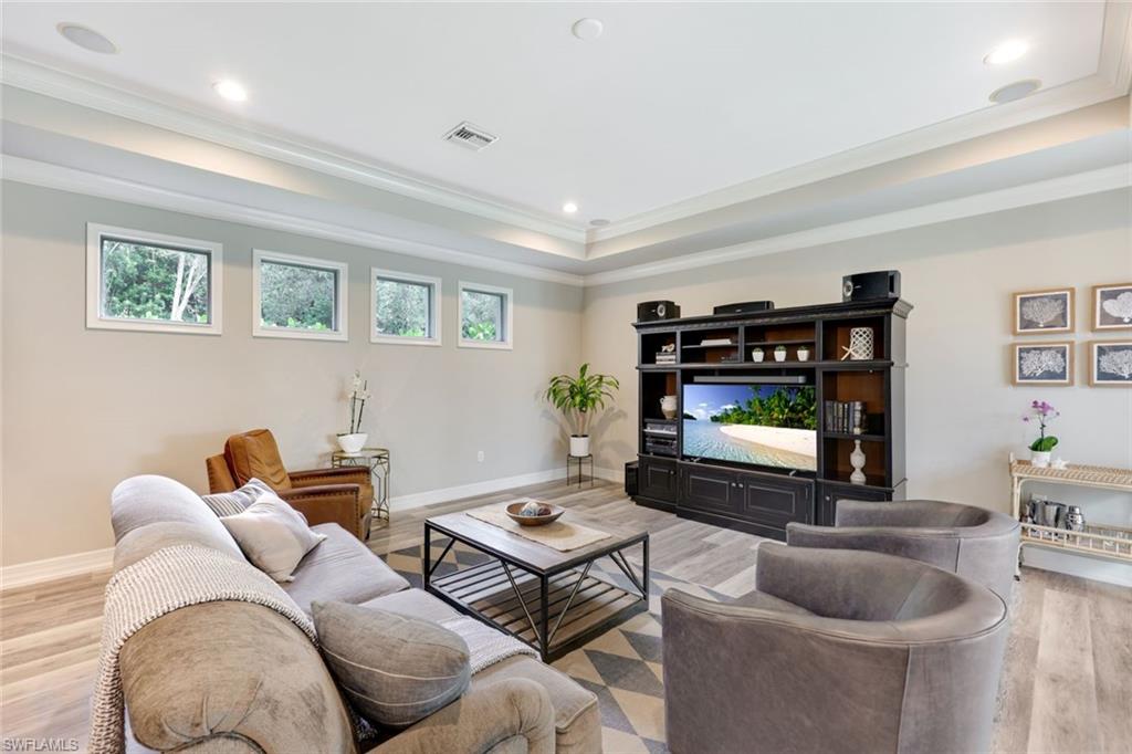 3960 Deep Passage Way Naples, FL 34109 - Photo 16 of 34 Spacious family room featuring elegant tray ceilings, offering a delightful view of the inviting pool area.