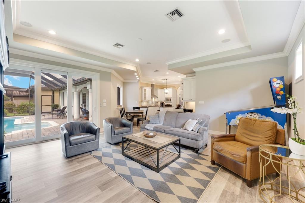 3960 Deep Passage Way Naples, FL 34109 - Photo 17 of 34 Living room featuring a raised ceiling, light wood-type flooring, ornamental molding, and recessed lighting