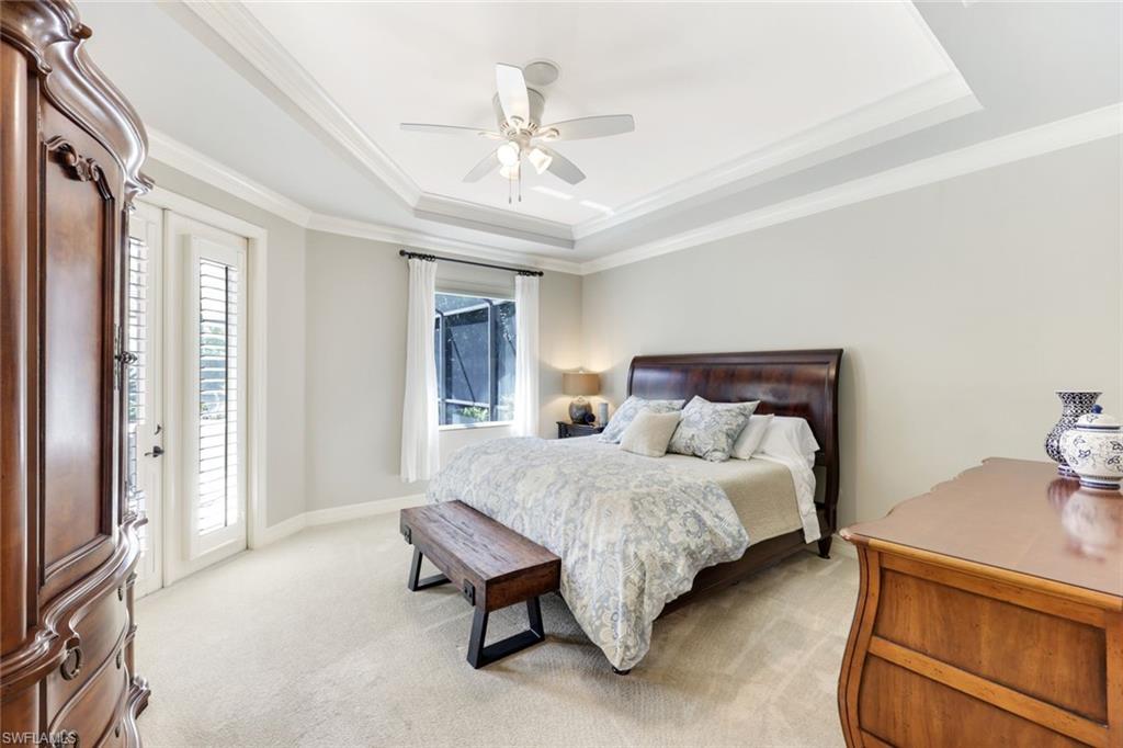 3960 Deep Passage Way Naples, FL 34109 - Photo 20 of 34 Spacious Primary Bedroom featuring elegant crown molding and a luxurious tray ceiling, complemented by plush, comfortable carpeted flooring.
