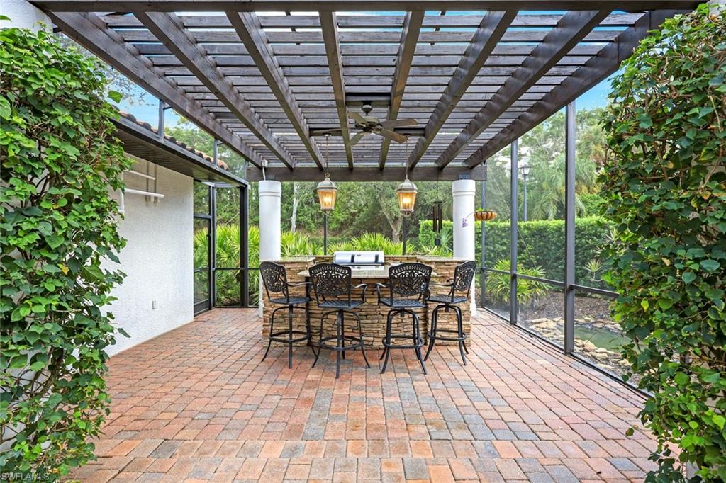 3960 Deep Passage Way Naples, FL 34109 - Photo 9 of 34 Screened-in summer kitchen featuring a built-in grill, a convenient refrigerator, and a practical sink, all elegantly situated beneath a beautifully crafted wood pergola,
