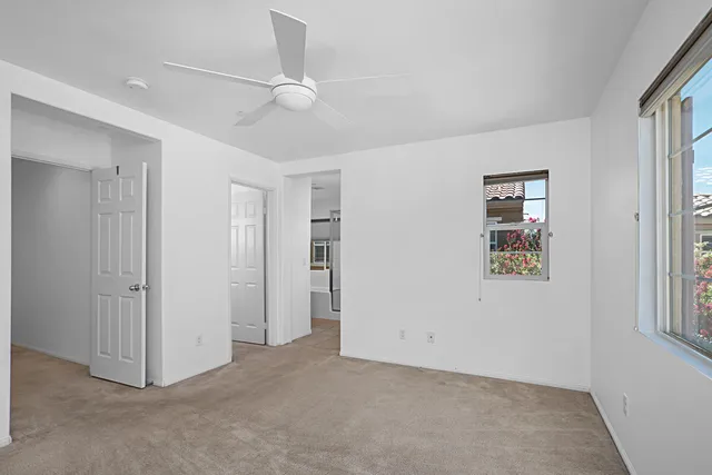 an empty room with windows and fan