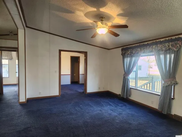 an empty room with windows and fan