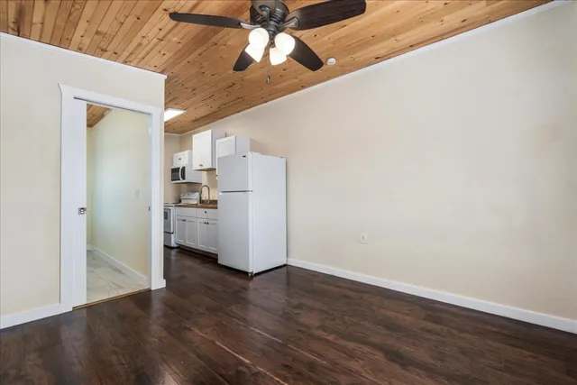 a view of a kitchen with wooden floor electronic appliances and cabinets