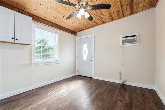 an empty room with wooden floor chandelier fan and windows