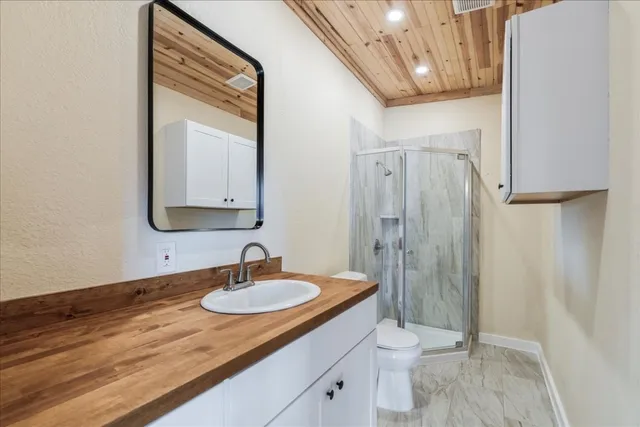 a bathroom with a granite countertop sink a toilet a mirror and shower