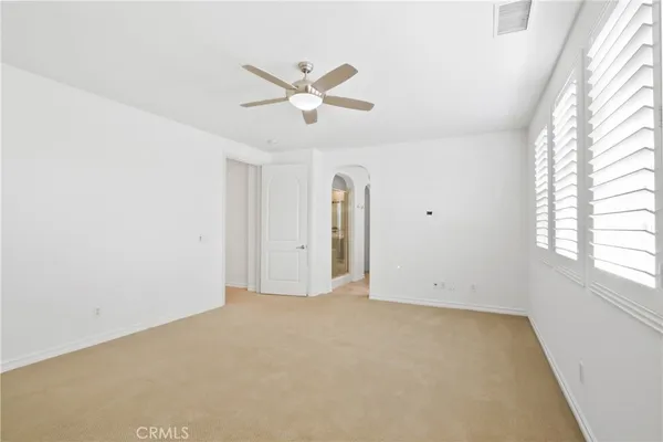 an empty room with windows and ceiling fan