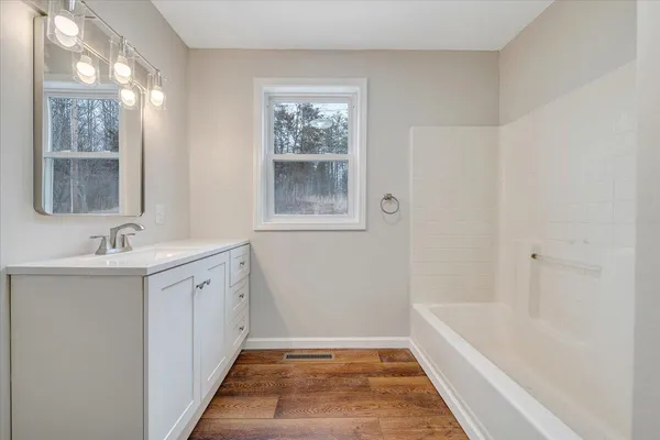 a bathroom with a tub sink and mirror